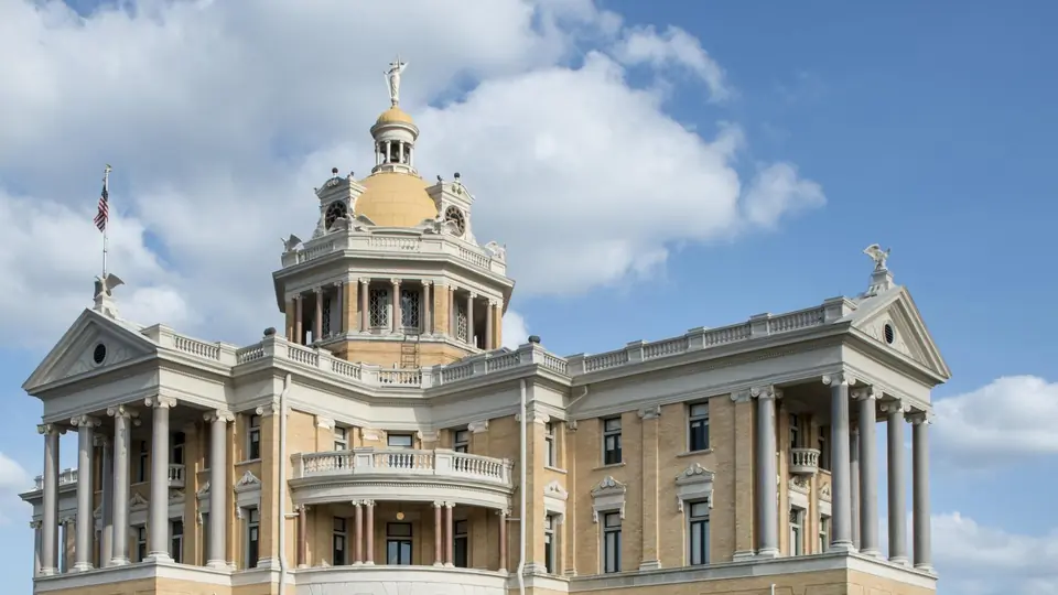 The old Harrison County Courthouse in Marshall, Texas, under a blue sky with clouds